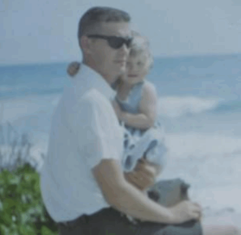 Dad holding me on his lap with the sea in the background.